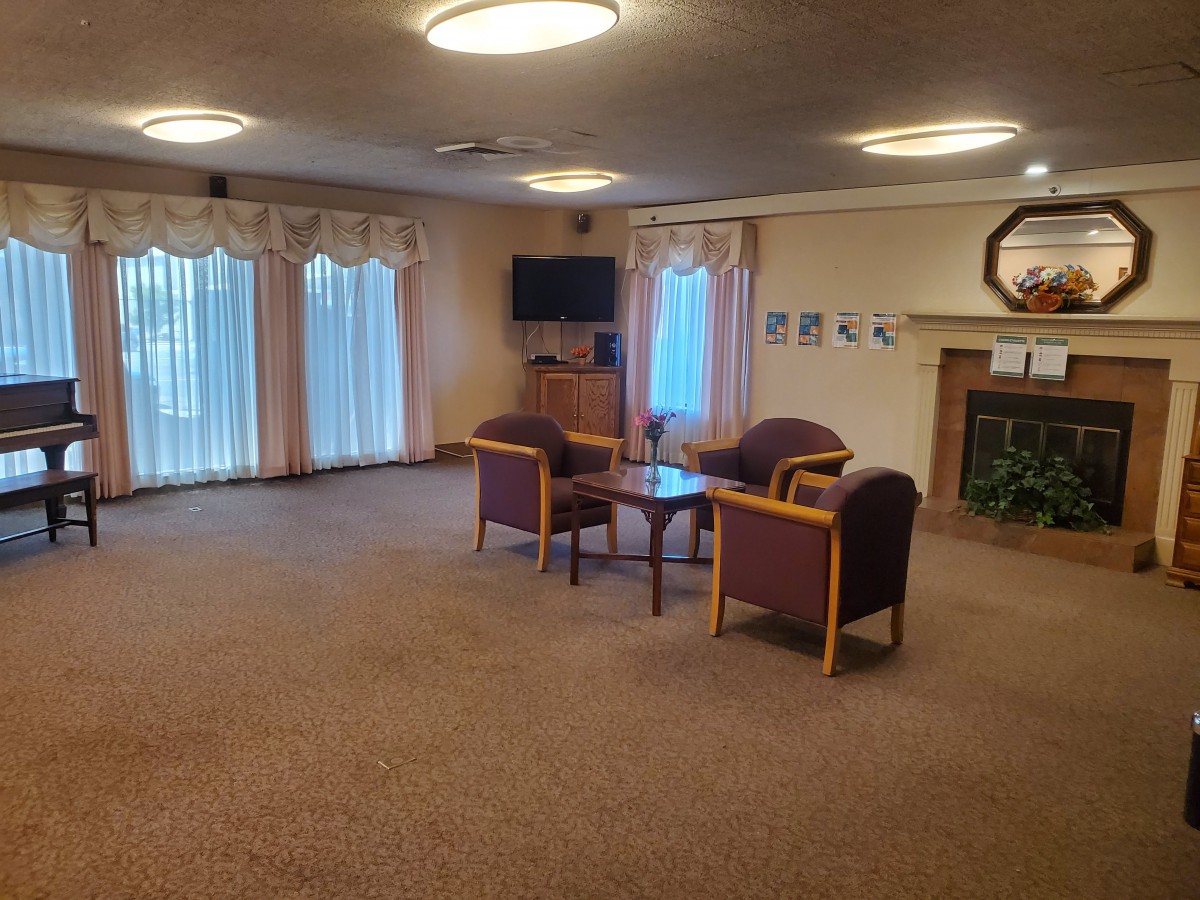 A cozy living room with chairs, a coffee table, and a television.