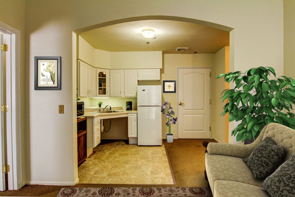 A cozy apartment kitchen with a comfortable living area, featuring a fridge and sofa.