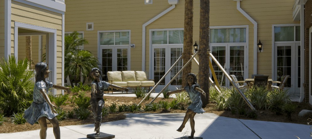 Bronze sculptures of children playing in a garden setting.