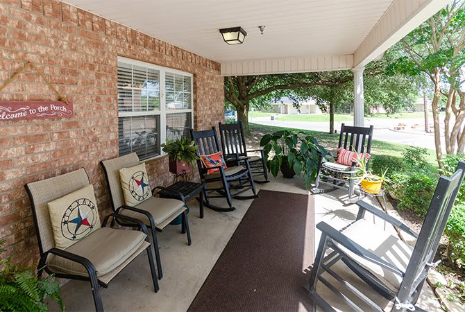 A cozy porch with rocking chairs and potted plants.