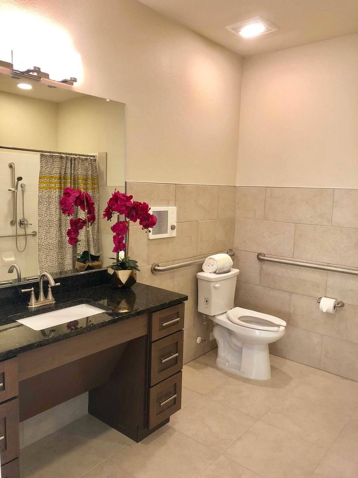 A modern bathroom with a toilet, sink, mirror, and decorative flowers.