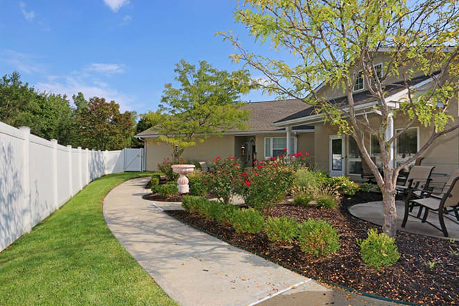 A well-maintained garden with a winding pathway leading to a charming house.