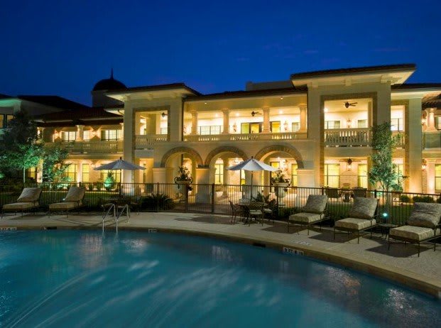 A luxurious house with a swimming pool illuminated at night.