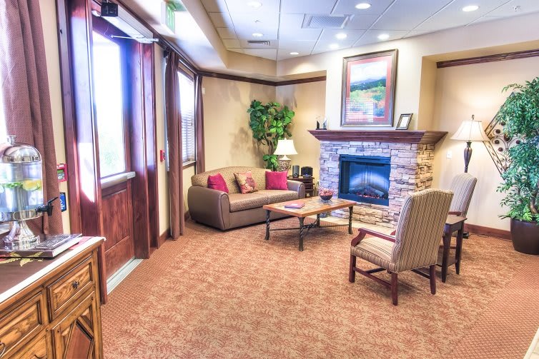 A cozy living room featuring a comfortable seating area with a sofa and armchair, complete with a fireplace and decorative elements.