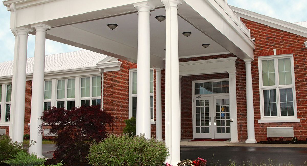 A building entrance with white columns and brick exterior.
