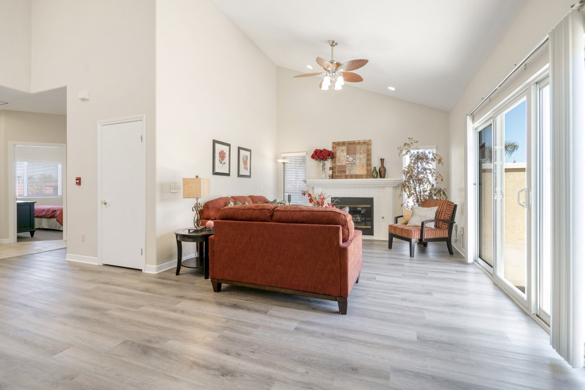 A cozy living room featuring a sofa set and armchair, with a fireplace as the focal point, decorated in warm tones and complemented by wood flooring.