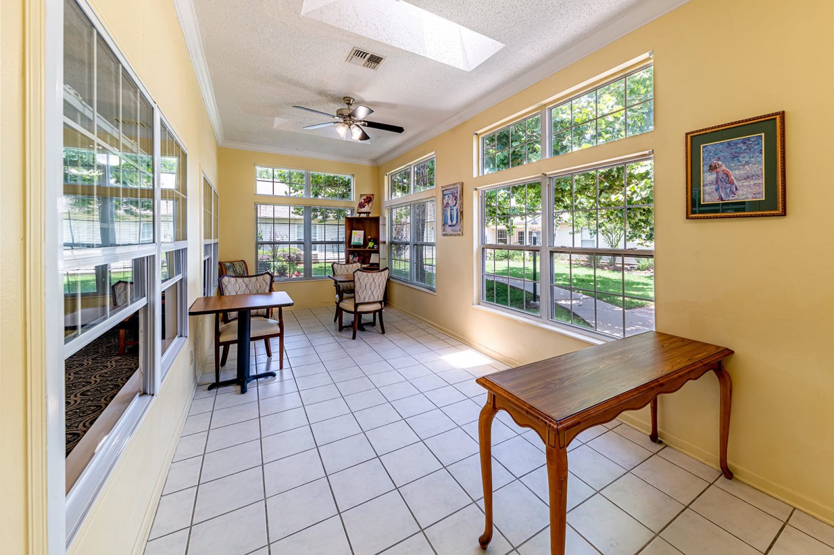 A bright sunroom with large windows, tiled flooring, and comfortable seating.