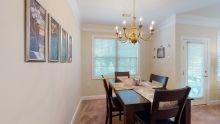 A cozy dining room with a wooden table and chairs, illuminated by a classic chandelier.