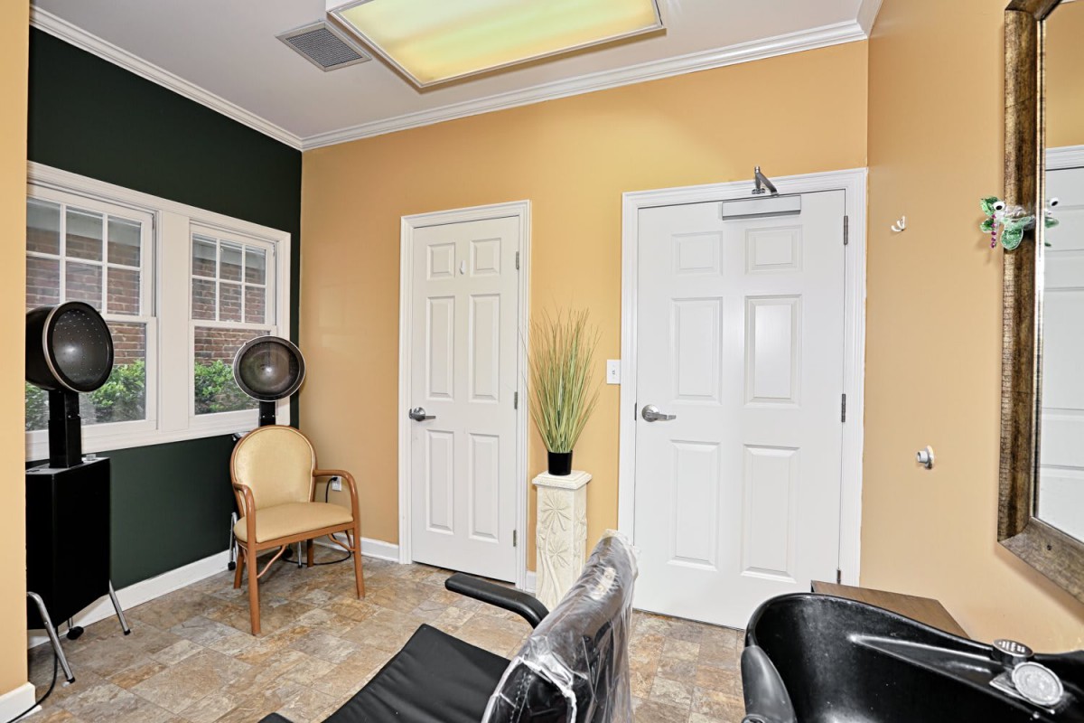 A salon interior with chairs and a hair dryer next to two closed doors.