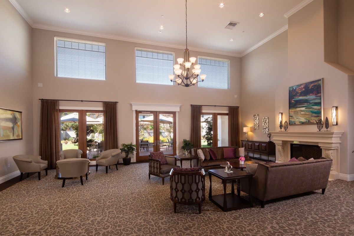 A spacious and elegantly decorated lobby featuring comfortable seating, a chandelier, and large windows.