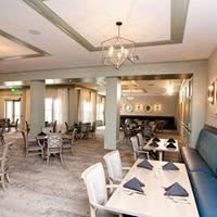 A well-lit restaurant dining area featuring neatly arranged tables with place settings.