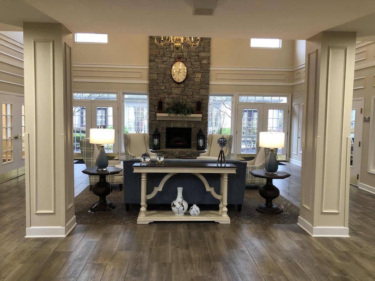 A modern living room with a central fireplace, elegant decor, and large windows allowing natural light to fill the space.
