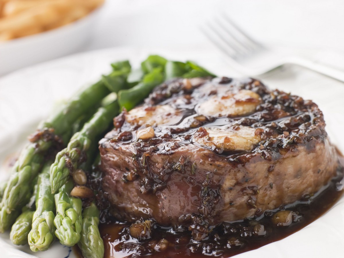 Grilled steak served with asparagus on a white plate.