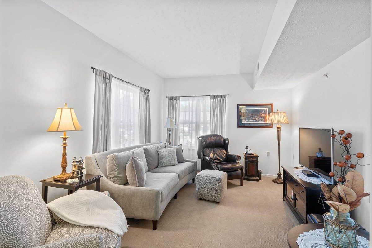 A cozy and well-lit living room featuring a comfortable sofa, armchair, and TV setup.
