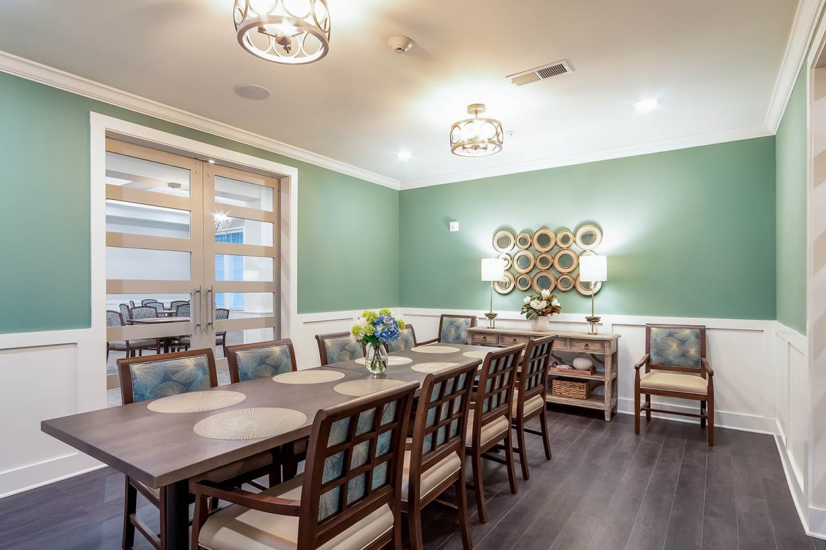 A modern dining room with green walls, elegant furniture, and stylish lighting fixtures.