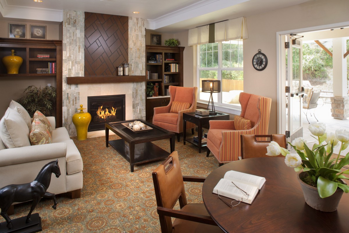 A cozy living room with a fireplace, armchairs, and bookshelves.