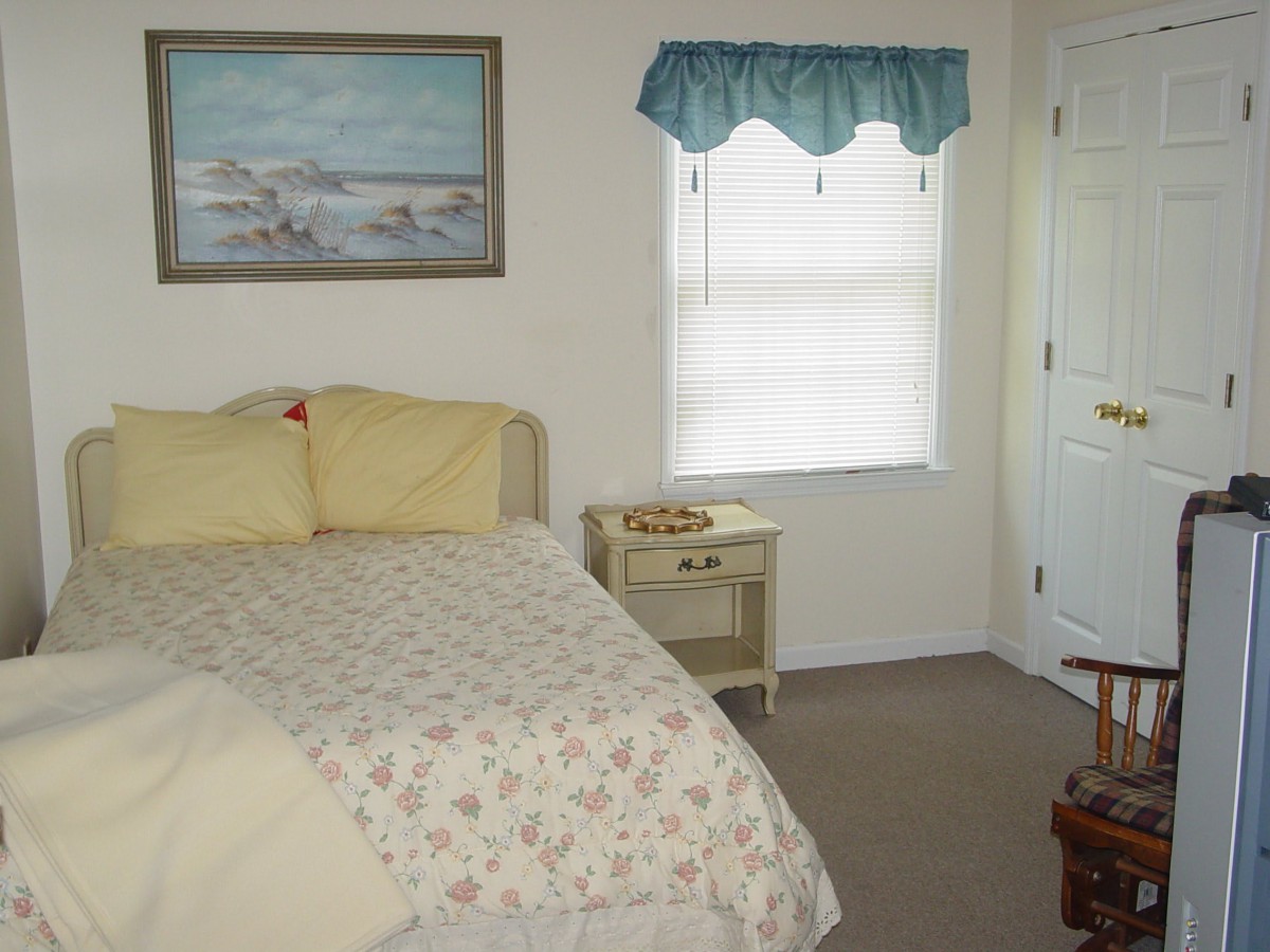 A cozy bedroom with a bed, nightstand, and window adorned with blue curtains.