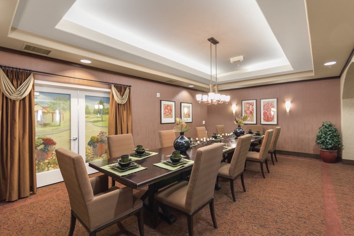 A beautifully decorated dining room with a long table, upholstered chairs, and elegant lighting.