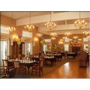 A spacious and elegantly decorated restaurant dining area with chandeliers, neatly arranged tables, and chairs.
