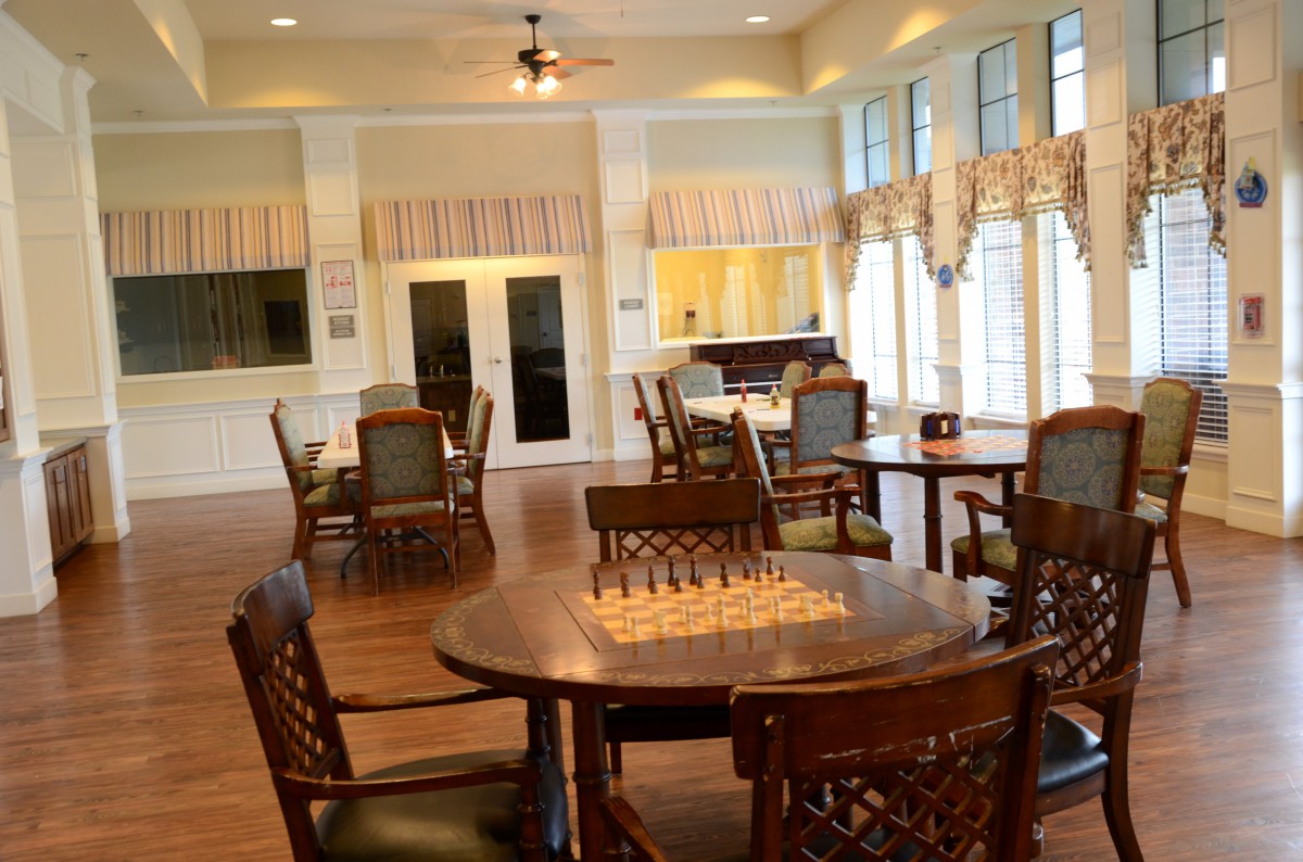 A spacious game room with a chessboard setup on a wooden table surrounded by chairs.