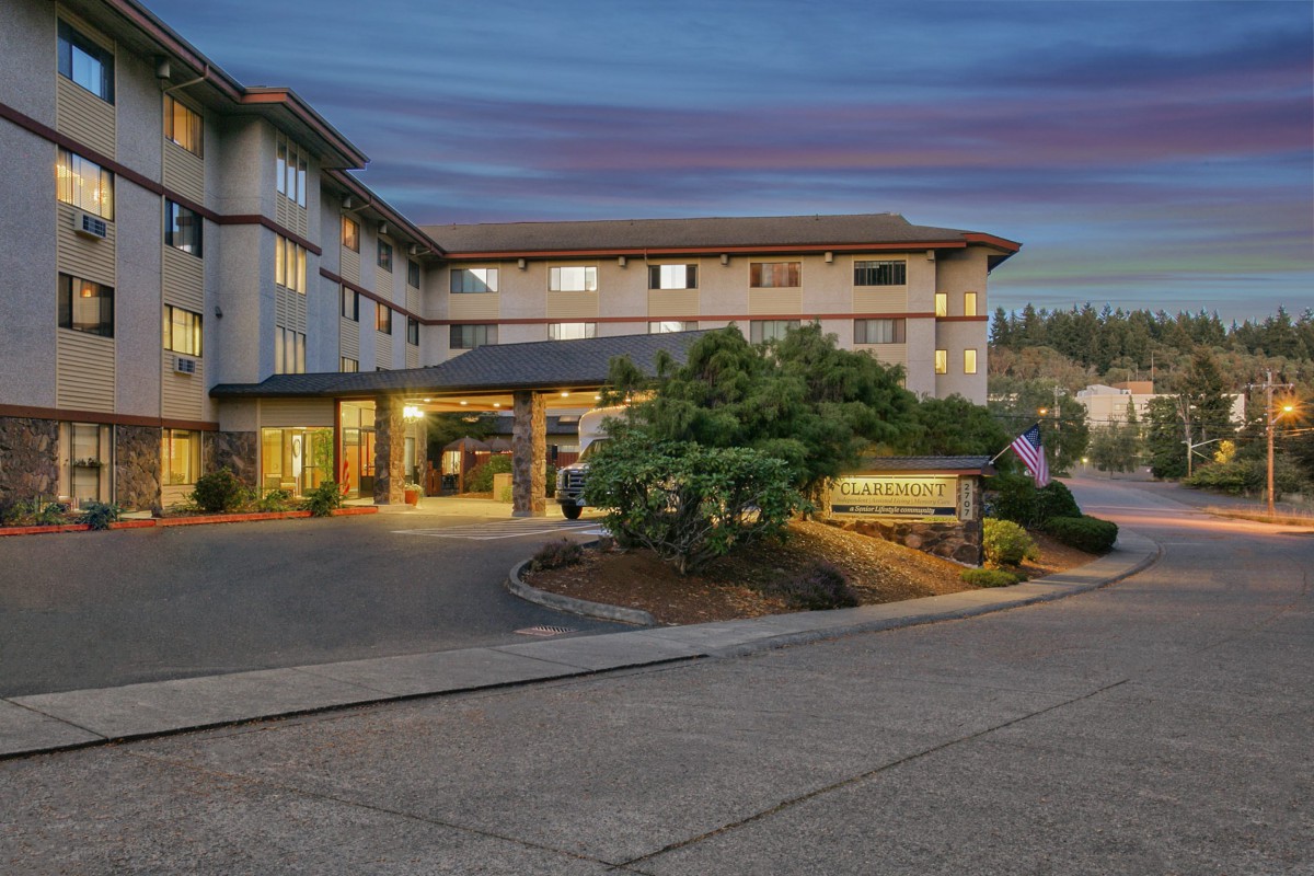An evening view of a hotel entrance with landscaped surroundings.