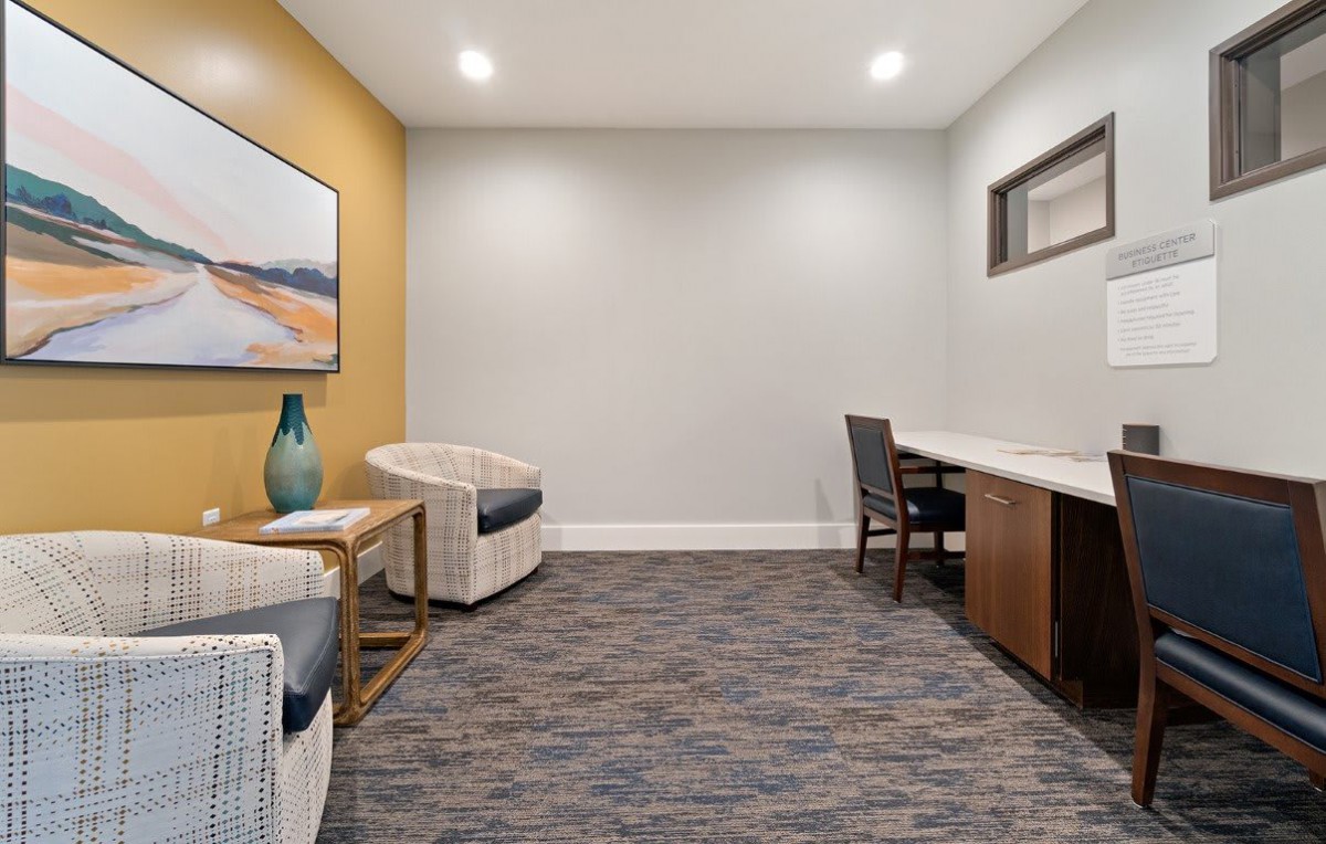 A modern office space with a desk, chairs, and artwork on the wall.