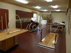 A rehabilitation therapy room equipped with exercise machines and parallel bars.