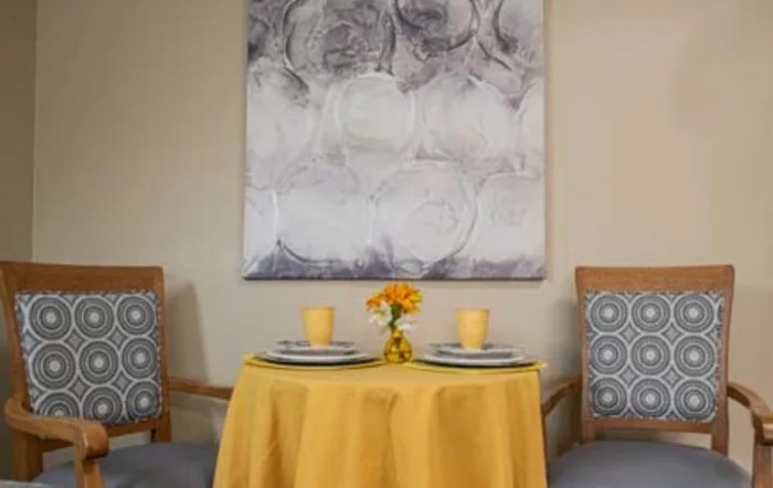 A cozy dining setup with a yellow tablecloth and elegant artwork in the background.