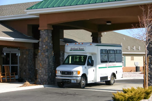 A white bus parked near the entrance of a building with a stone facade.