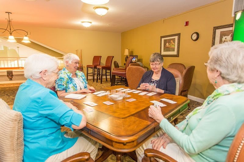 A group of elderly women enjoying a card game in a cozy, indoor setting.