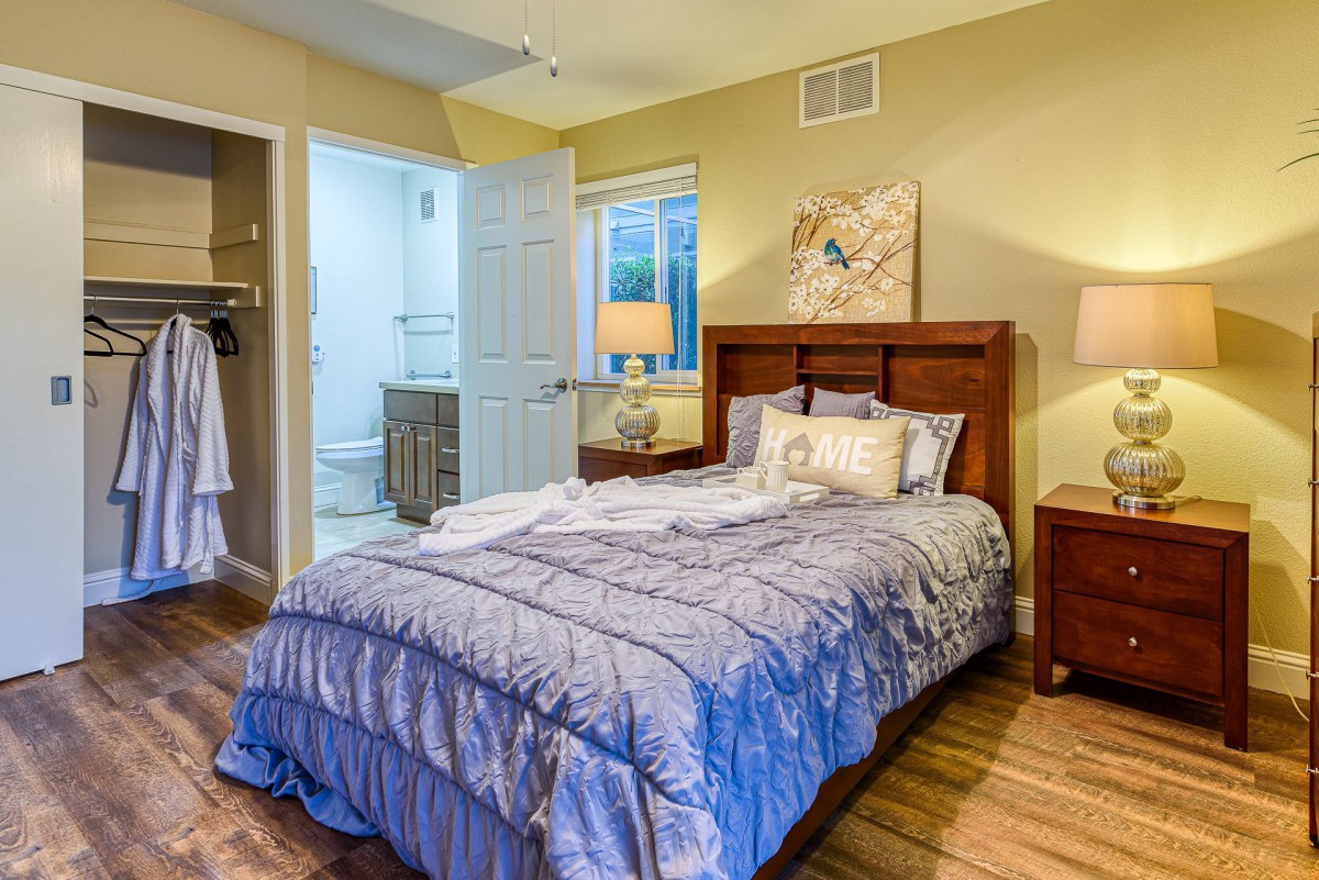 A cozy bedroom with a neatly made bed, wooden furniture, and soft lighting.
