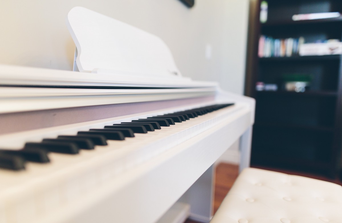 A sleek white piano in a cozy music room setting.