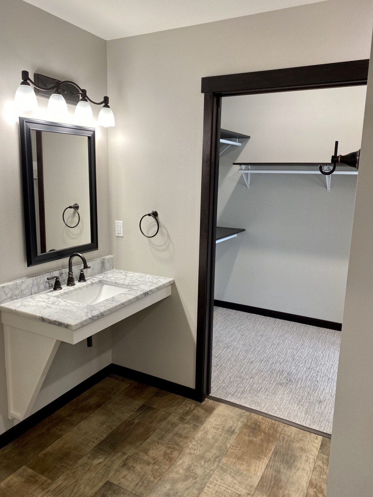 A bathroom with a wall-mounted sink and adjacent walk-in closet.