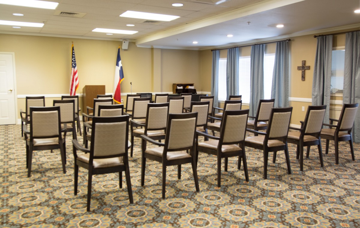 Empty conference room with arranged chairs and flags at the front.
