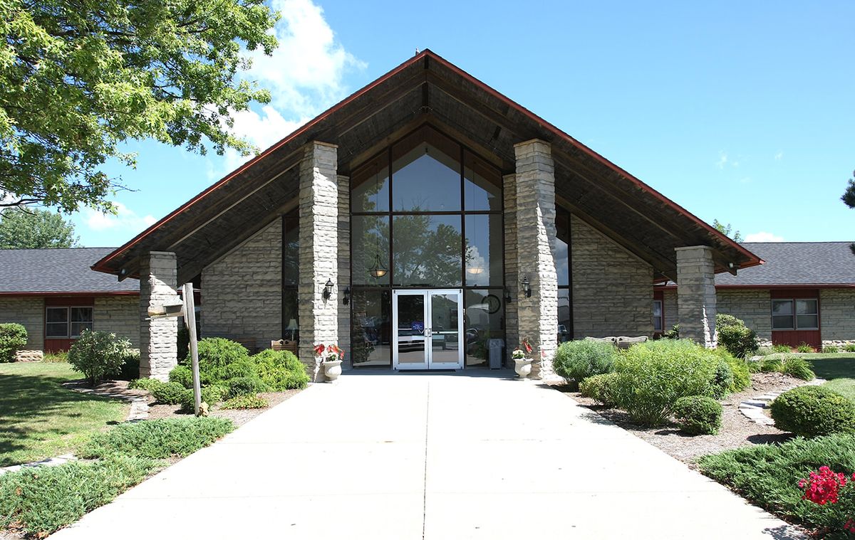 Front view of a church with stone walls and glass doors.