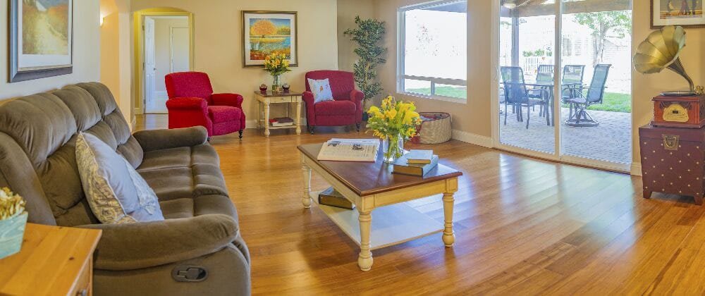 A cozy living room with red chairs, a coffee table, and decorative elements including flowers and artwork.