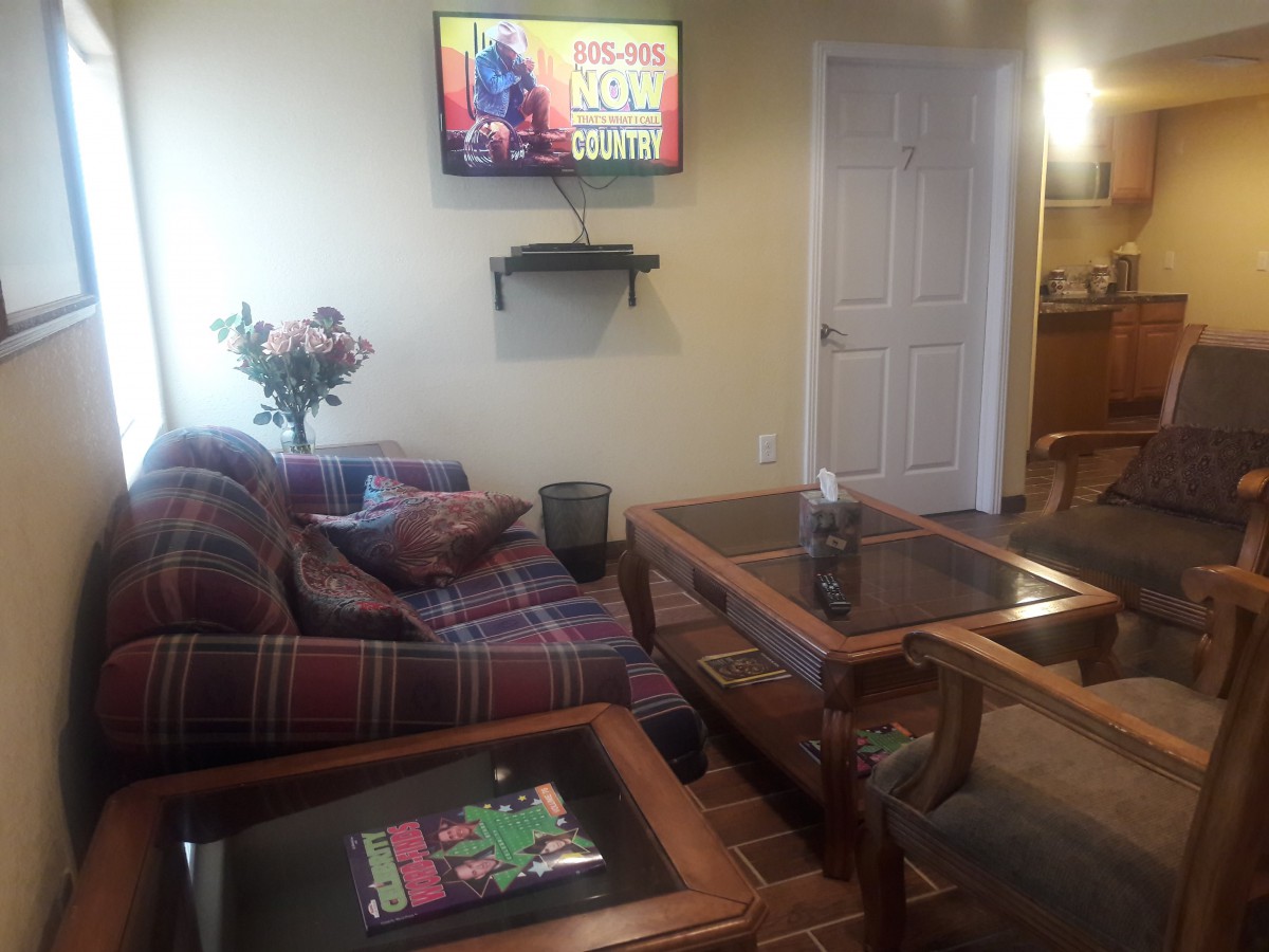 A cozy living room with a sofa, glass coffee table, and a television mounted on the wall.