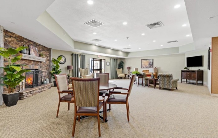 A spacious, elegantly furnished lounge area with several chairs and tables, featuring a cozy atmosphere with neutral tones and modern decor.