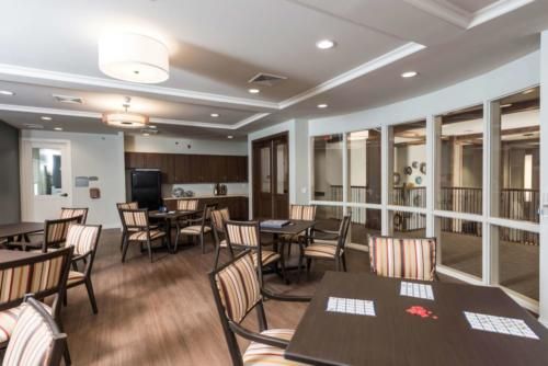 A modern dining area with neatly arranged tables and chairs, featuring wood flooring and stylish lighting.