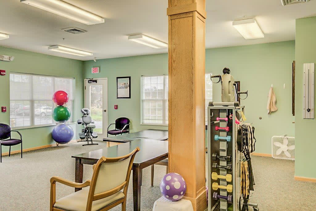 A brightly lit exercise and therapy room with fitness equipment and seating.
