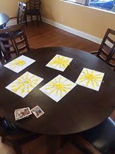 A round table displaying several children's drawings of yellow suns.