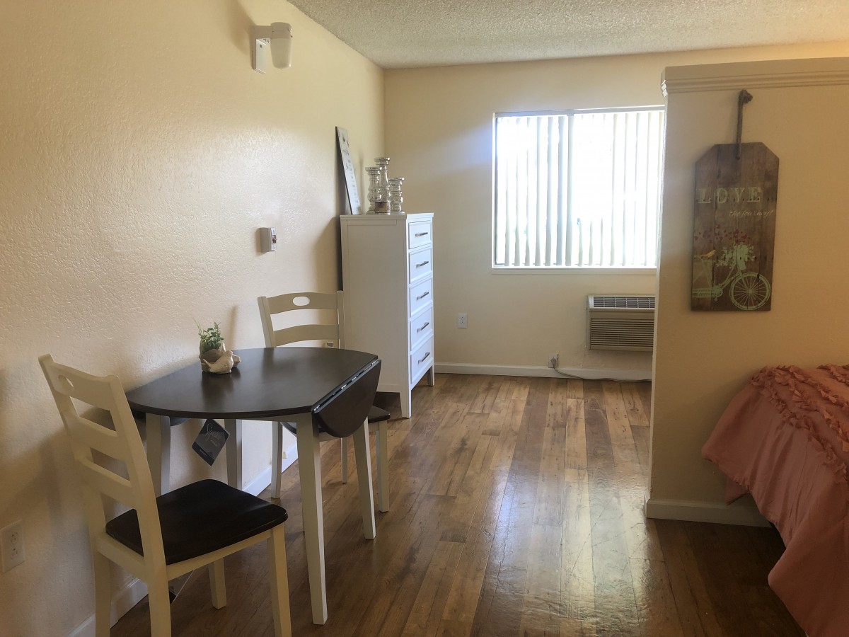 A cozy apartment interior with a small dining table, window, and hardwood floors.