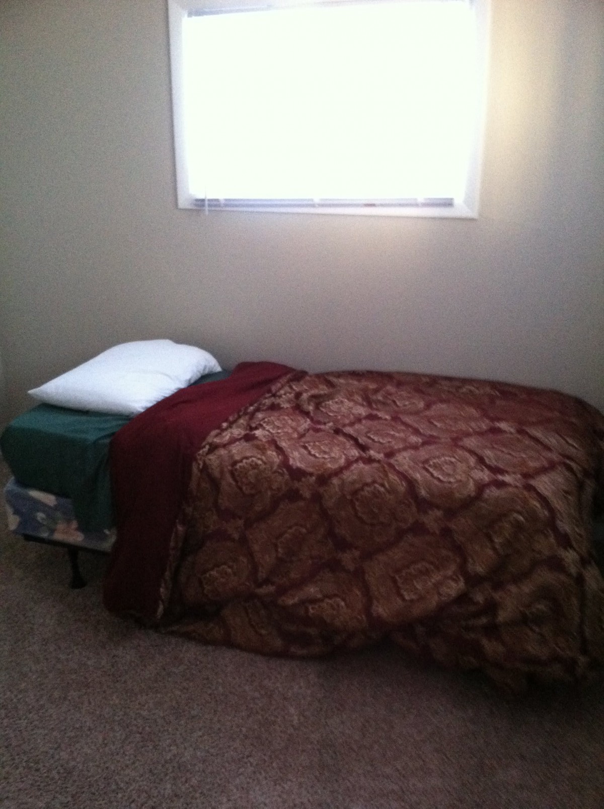 A simple bedroom with a single bed under a window.