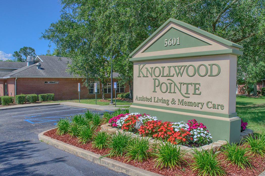 Entrance sign for Knollwood Pointe Assisted Living & Memory Care surrounded by landscaped flowers.
