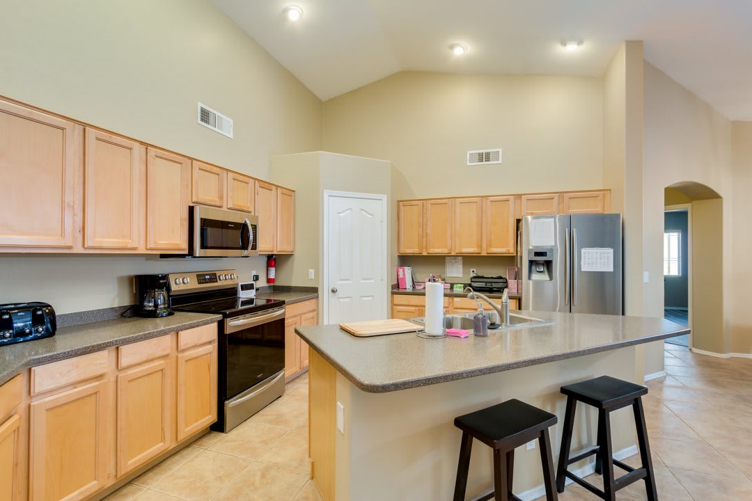 A modern kitchen featuring stainless steel appliances and a spacious countertop with bar stools.