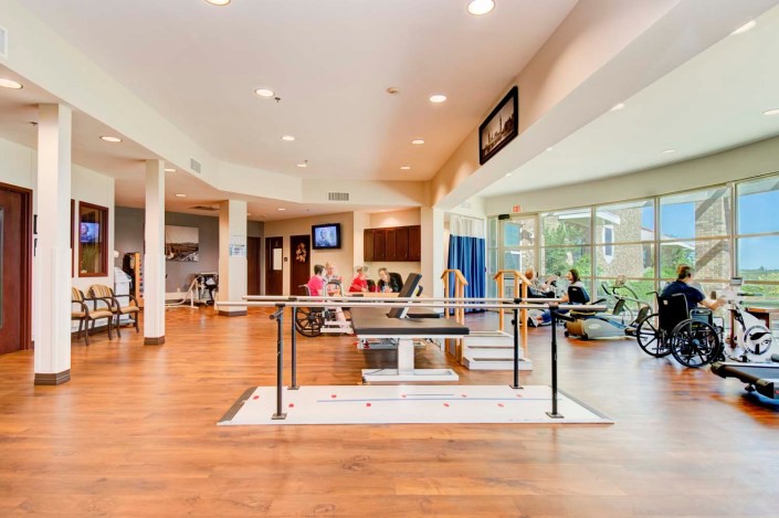 A spacious rehabilitation center equipped with exercise machines and parallel bars for physical therapy.