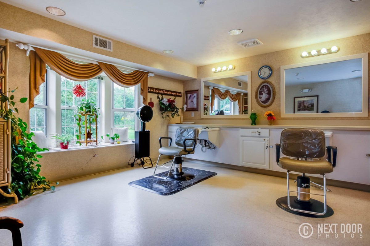 A well-lit hair salon interior featuring a styling chair, large mirror, and decorative elements by the window.