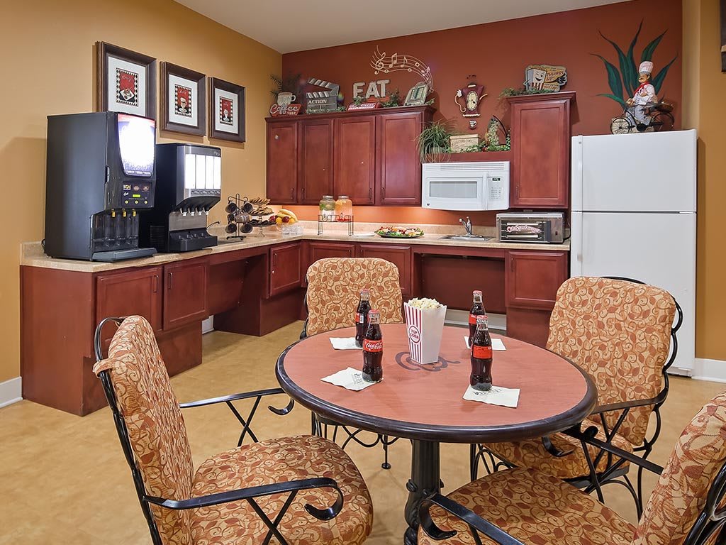 A cozy kitchen and dining area featuring a round table with chairs, a coffee station, and modern appliances.