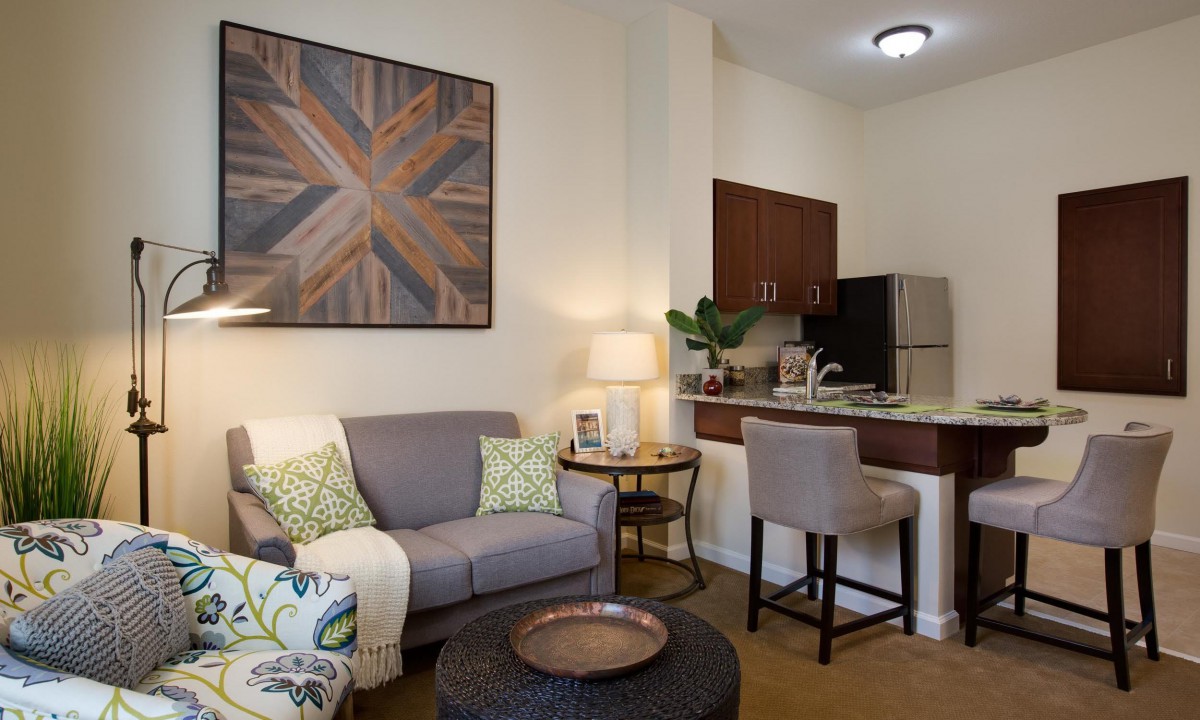 A cozy living room connected to a kitchen area with modern decor and seating.