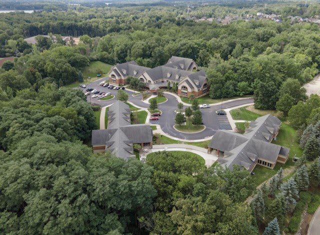 Aerial view of a building complex surrounded by lush greenery.